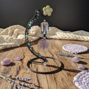 Decorative hanging ornament with a flower and crocheted pieces on a wooden table.