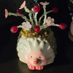A cute pig-shaped vase with flowers and cherries.