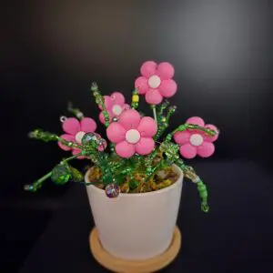 A small pot with delicate pink flower decorations against a dark background.