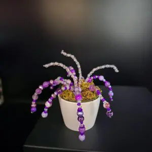 Decorative purple beaded plant in a white pot.