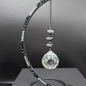 Crystal prism hanging from a decorative metal stand.