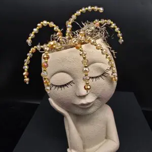 A serene sculpture with closed eyes and golden tendrils on its head.