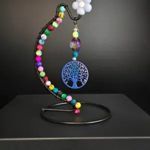 Colorful beaded tree of life keychain on a curved stand.
