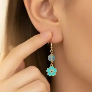 Close-up of a hand holding a dangling flower-shaped earring.