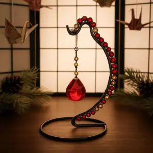 Elegant snake-shaped ornament with a red gem, set against a softly lit background.
