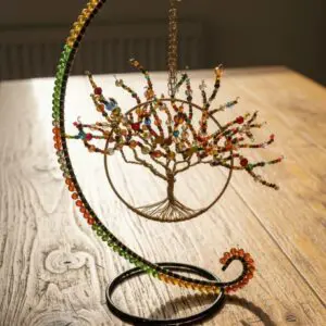Intricate wire tree sculpture with colorful beads on a wooden table.