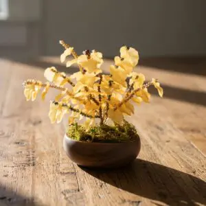 Miniature artificial yellow flowers in a small brown pot on wooden surface.