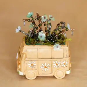 Miniature van filled with tiny plants and flowers.