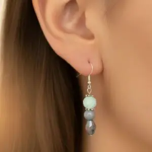 Elegant dangling earrings with white and gray beads on a woman's ear.