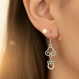Elegant silver earrings with intricate design worn on an ear.