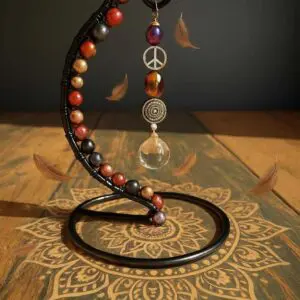 Artistic crescent-shaped sculpture with beads and a hanging glass orb casting intricate shadows.